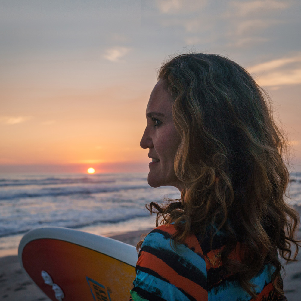 women surfer on beach at sunset
