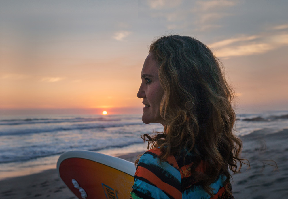 women surfer on beach at sunset