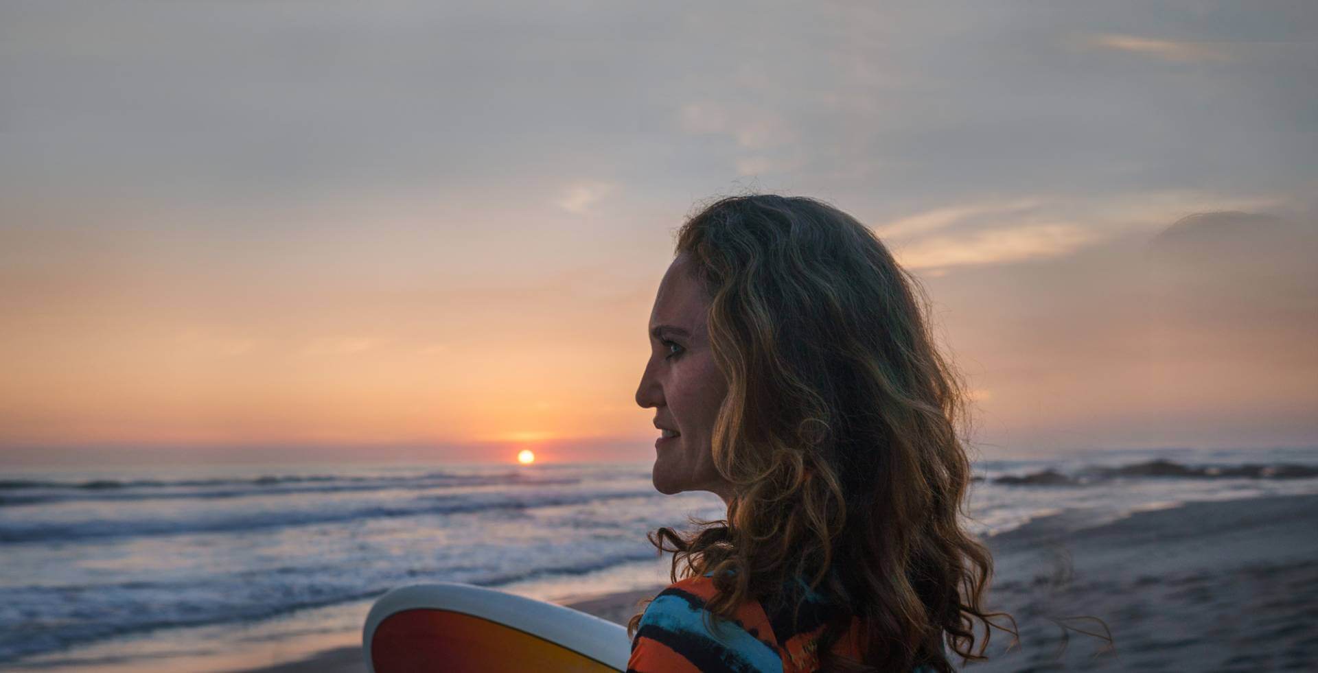 Mav surfer on beach at sunset - the founder of SoulPowerPilates,